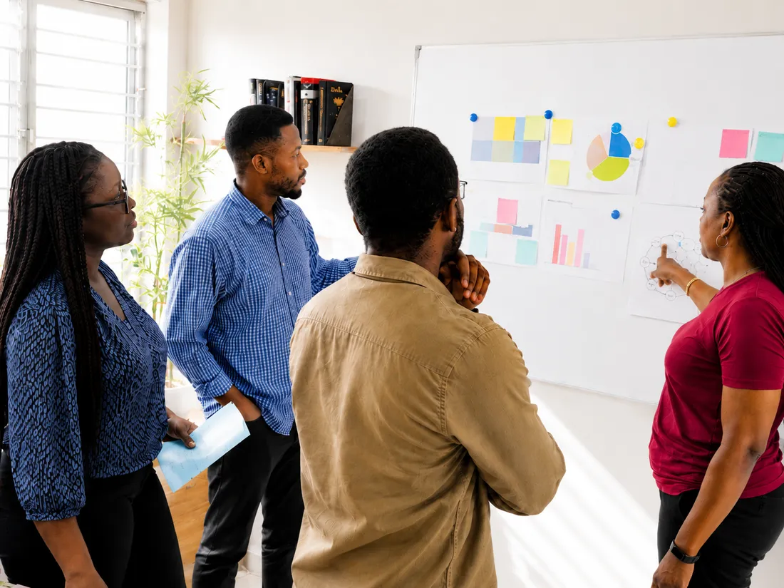 A Nigerian strategy team reviewing a connected campaign plan at a whiteboard in a Lagos office.